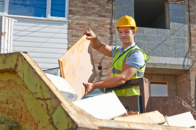 builder putting rubbish into a skip